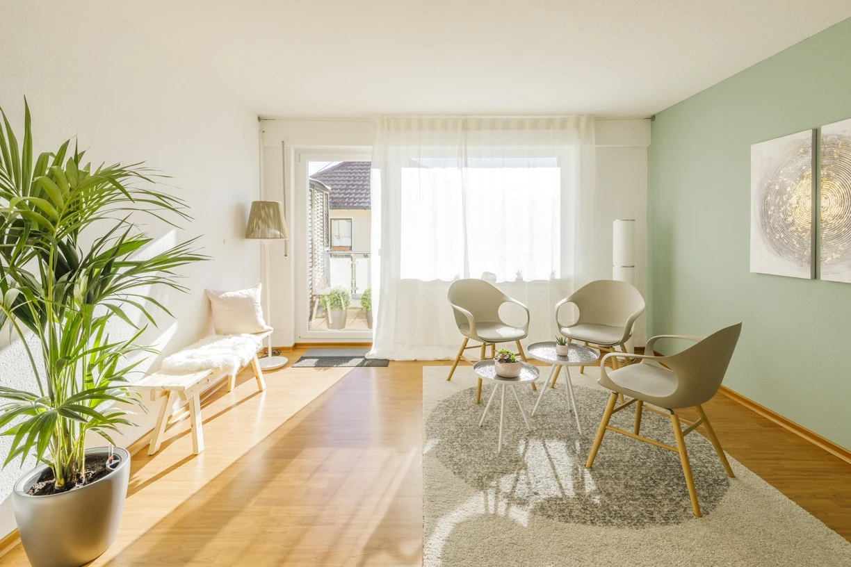Helles Wohnzimmer mit modernen Möbeln, Zimmerpflanze und Zugang zum Balkon.